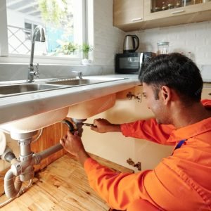 imgi_54_busy-young-mixed-race-plumber-orange-bodysuit-unscrewing-water-pipe-whi